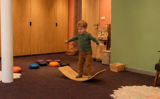 Kind balanceert op een wobbelbord in de praktijkruimte van Lightbulb